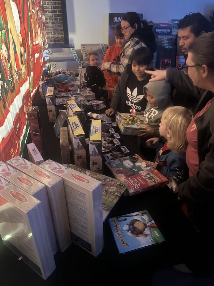 Kids and families picking out toys and games from tables at LLC North Pole Christmas.