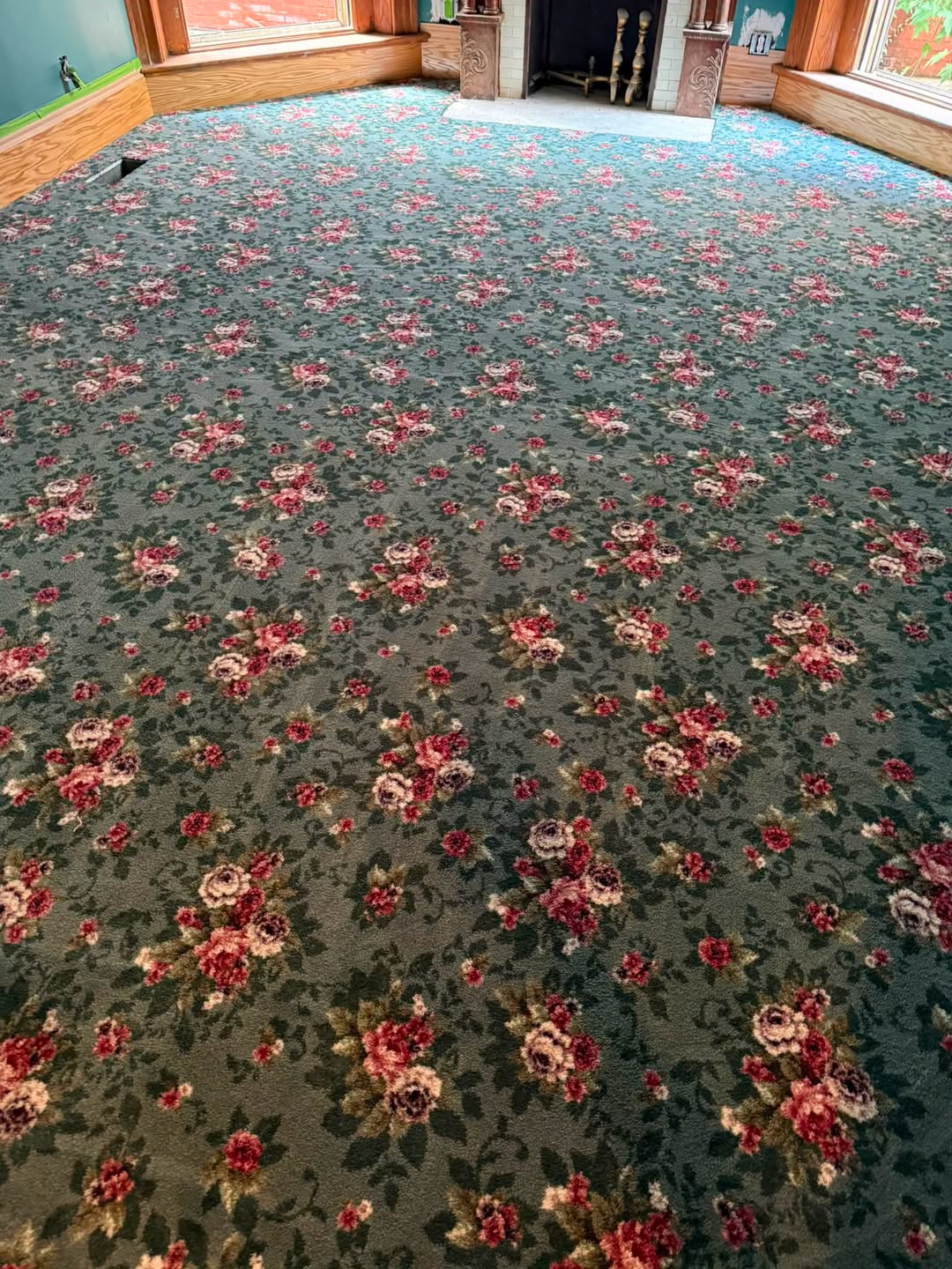 Teal carpet with a red rose pattern in a sitting room.