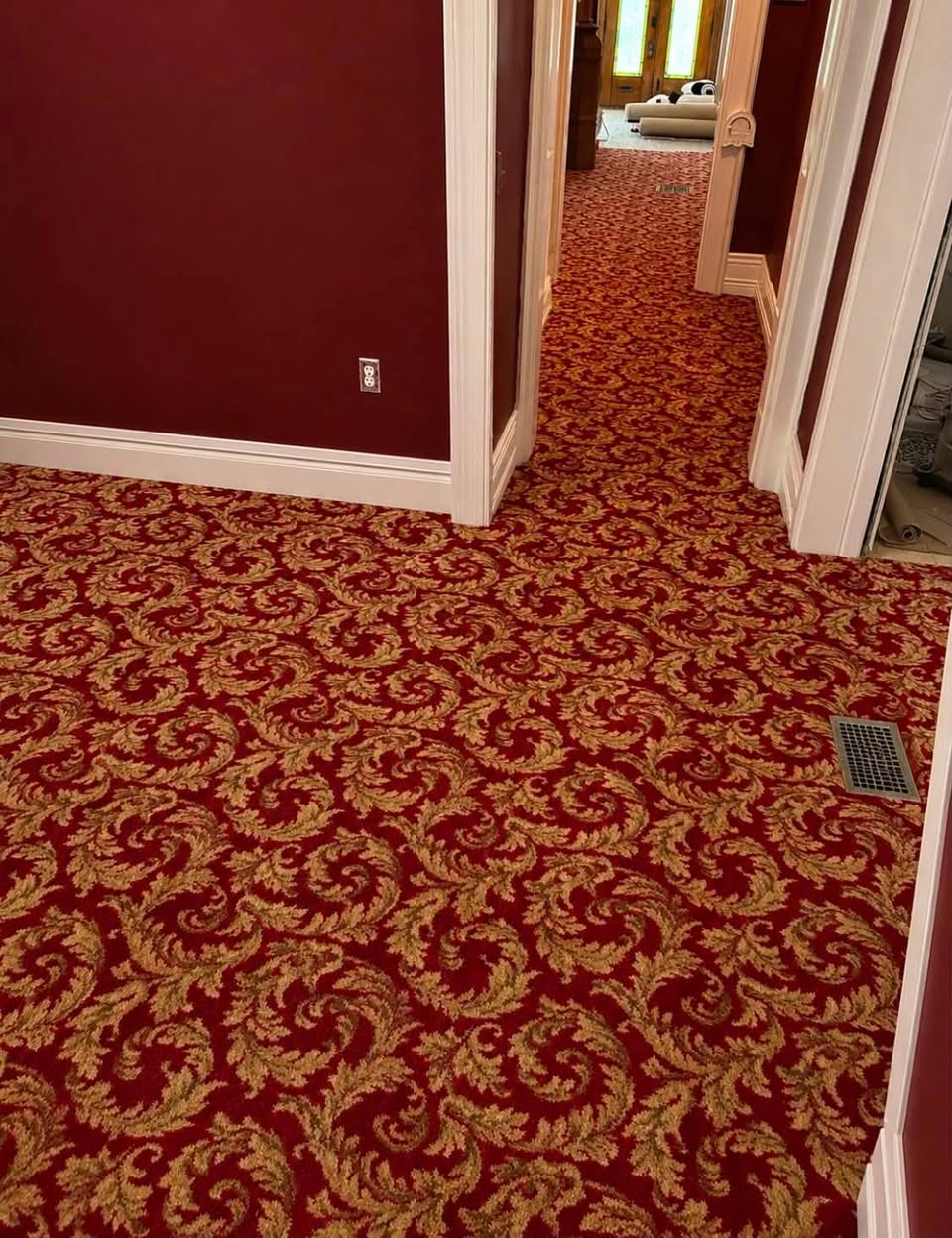 An ornate red and gold patterned carpet in a period home hallway.