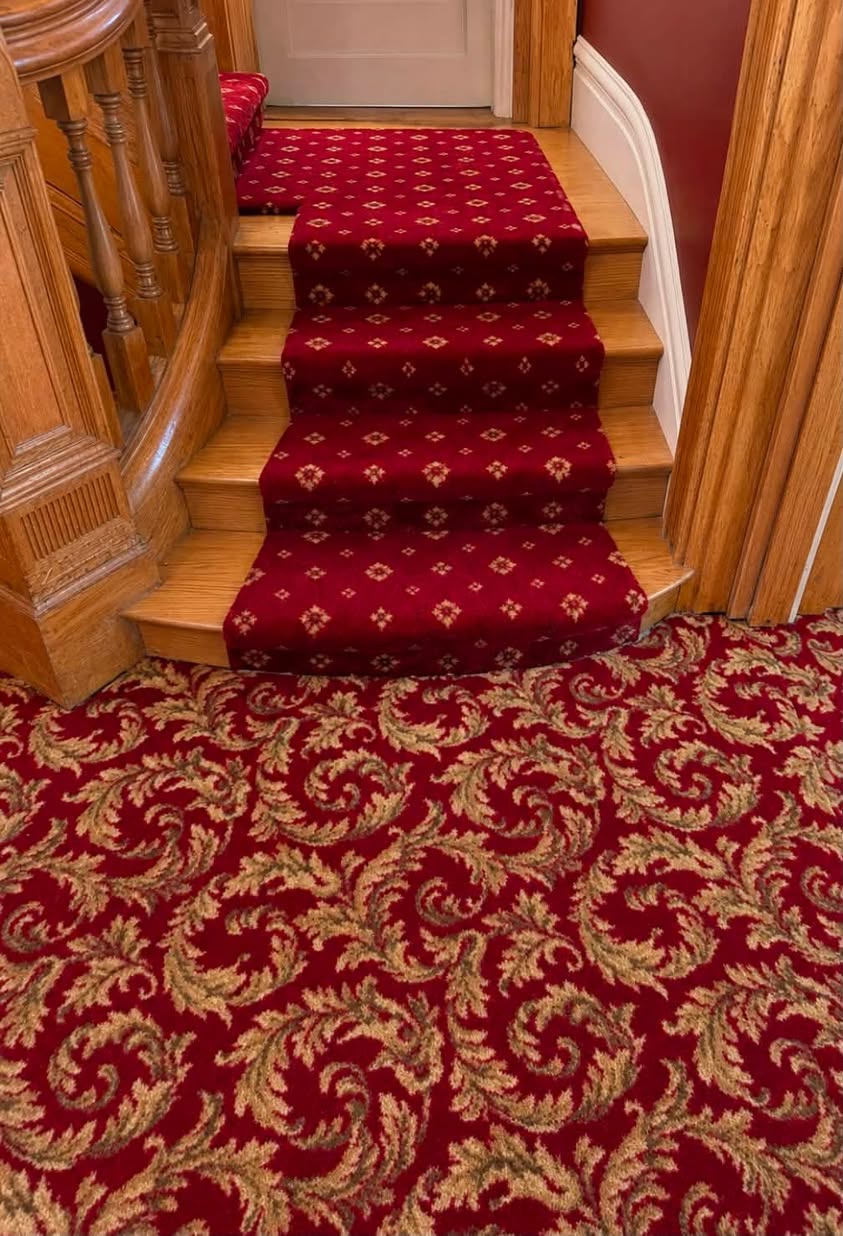 A red patterned stair runner leading to a matching wall-to-wall carpet.