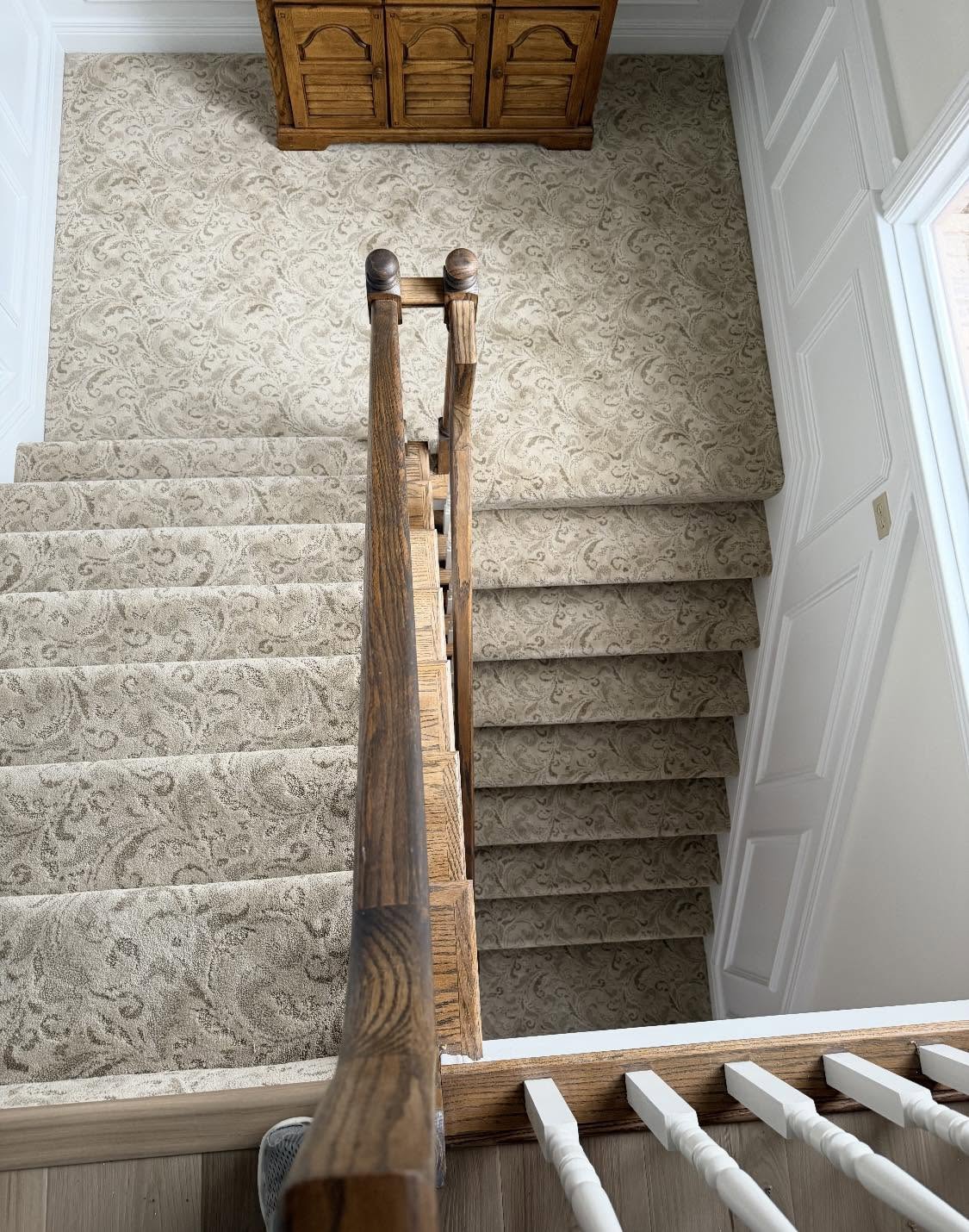 Cream patterned carpet on a staircase, seen from the landing above.