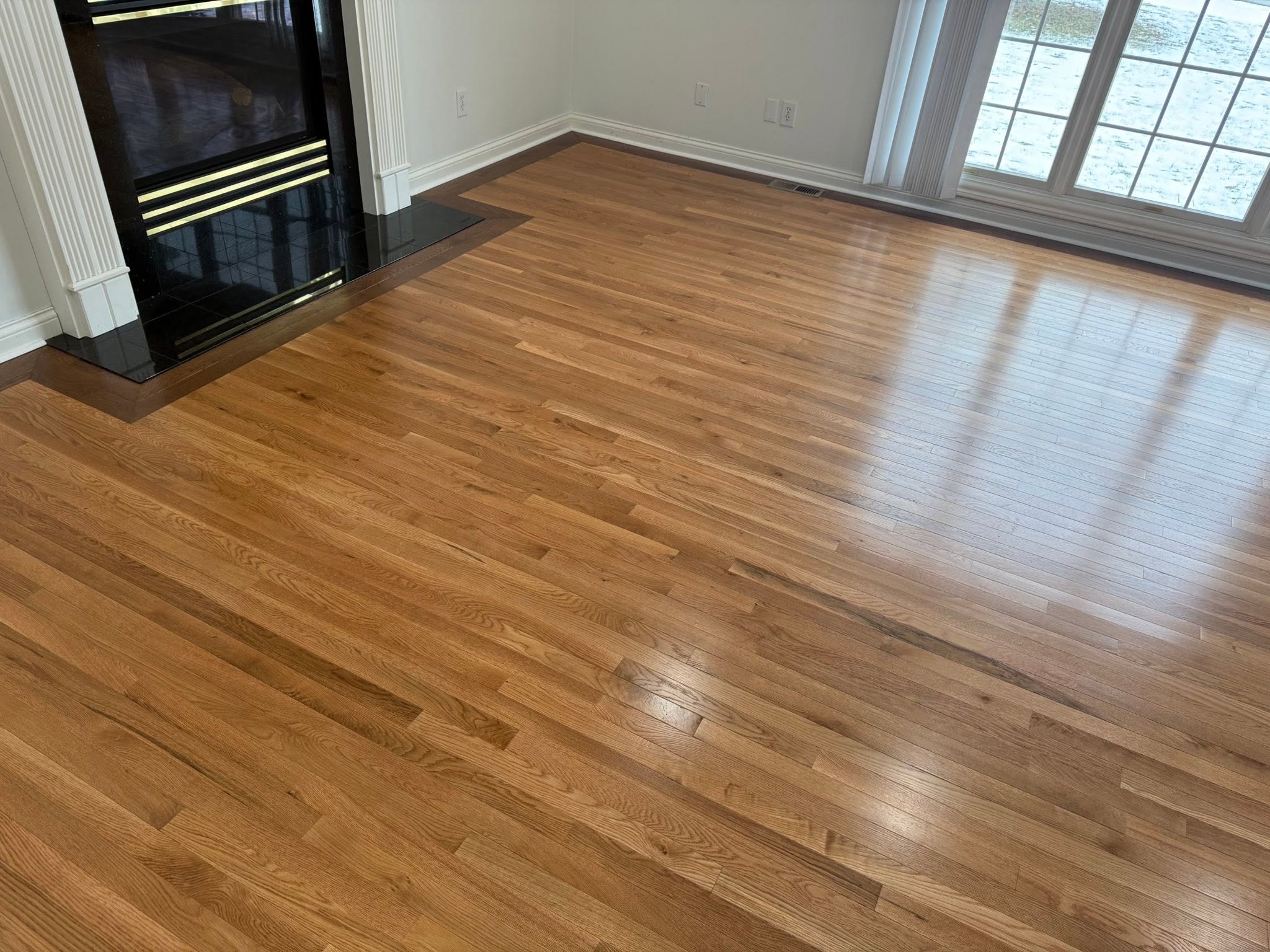 Natural oak hardwood flooring in a living room with a fireplace.
