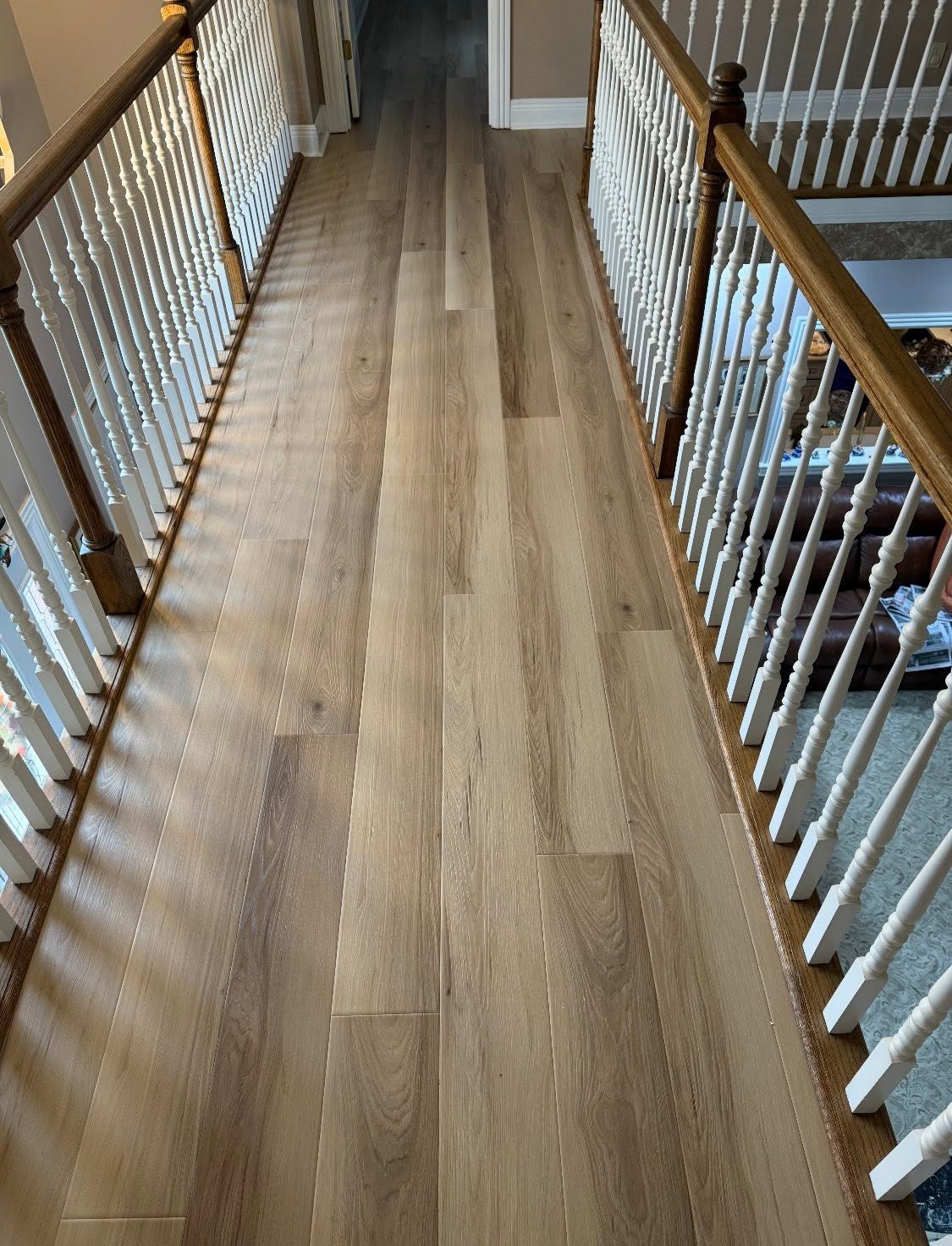 Wood-look plank flooring along an upstairs balcony with white railings.