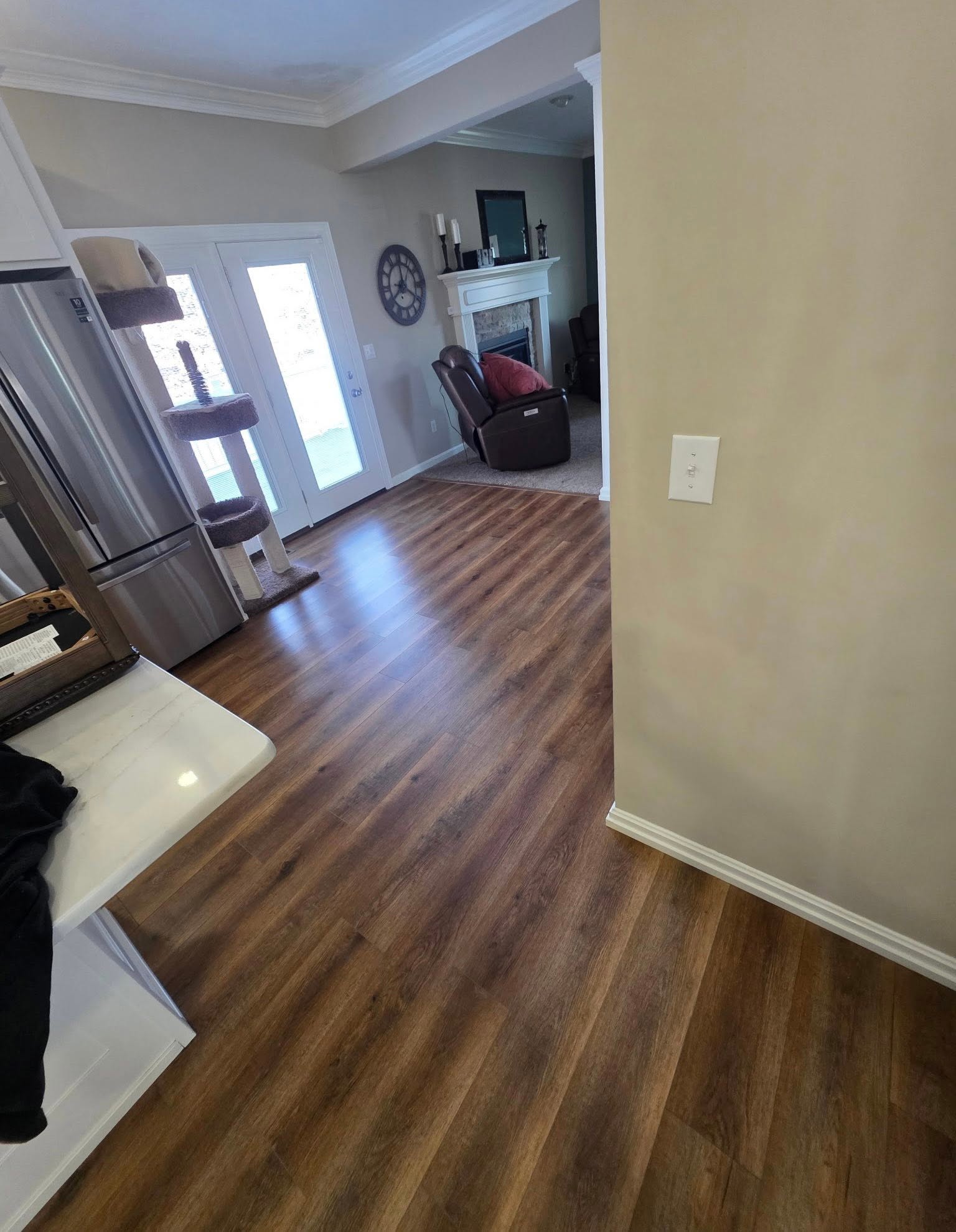 Wood-look flooring in a kitchen and living room with a stone fireplace.
