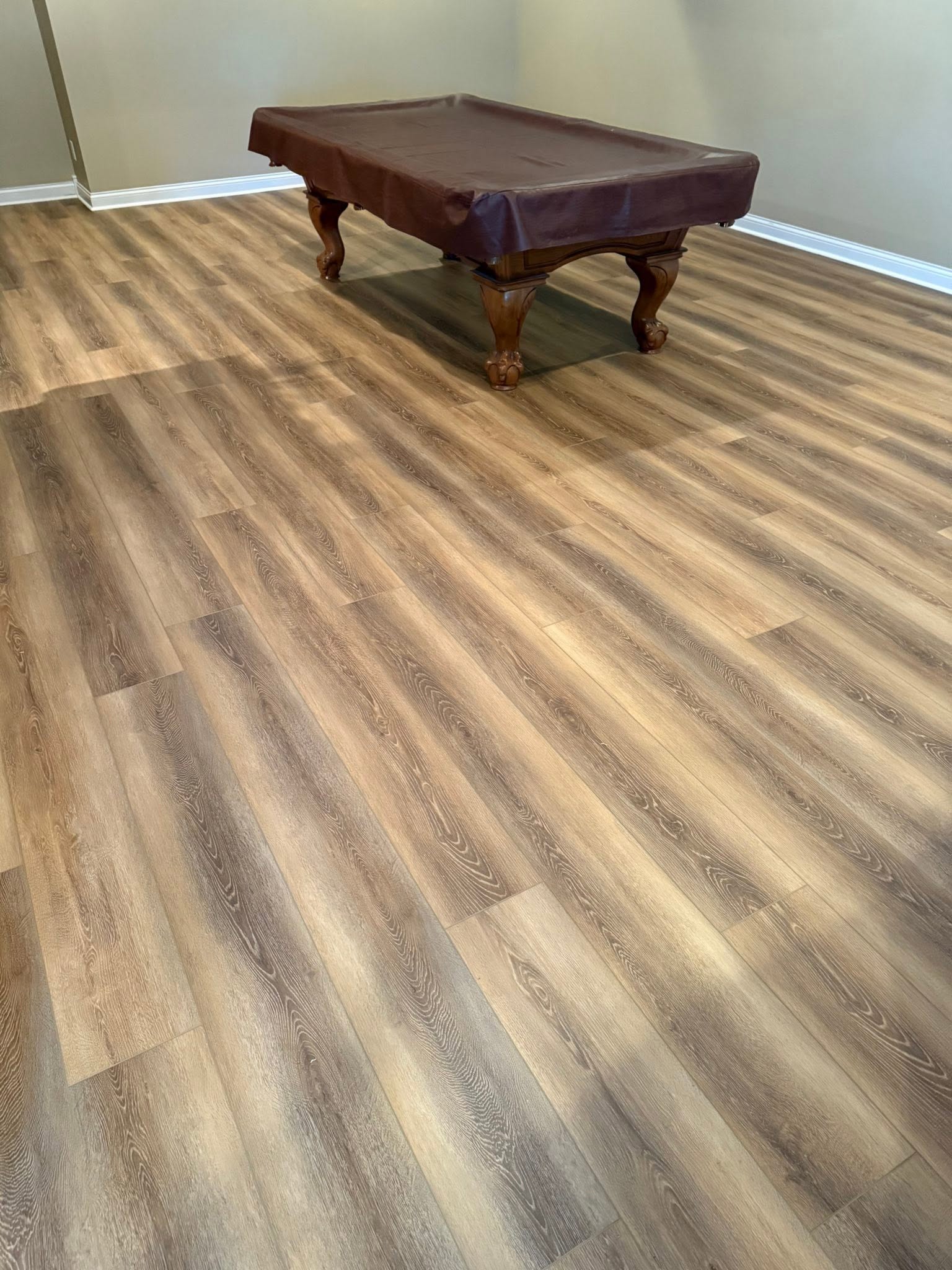Wood-look plank flooring in a game room with a pool table.