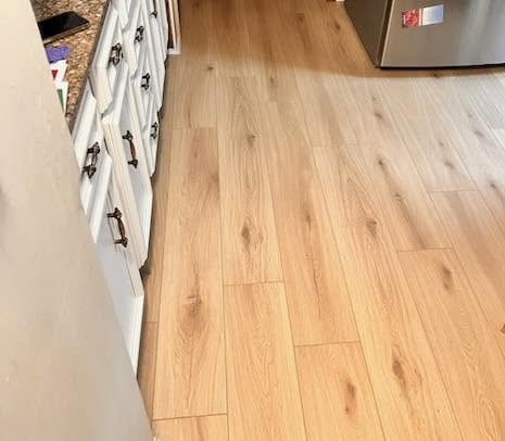 Honey wood-look flooring in a kitchen with white cabinets.