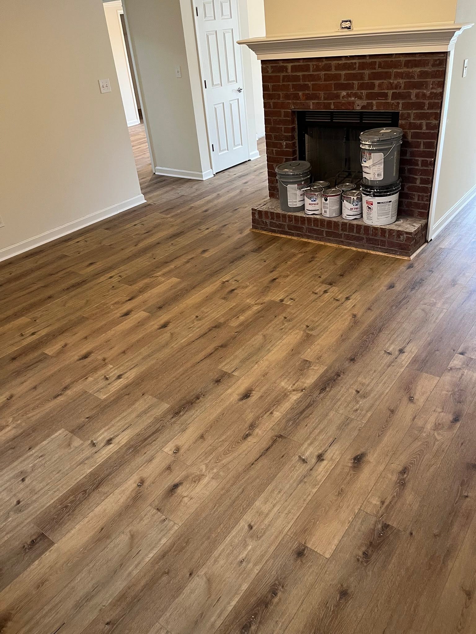 Wood-look plank flooring in a living room with a brick fireplace.