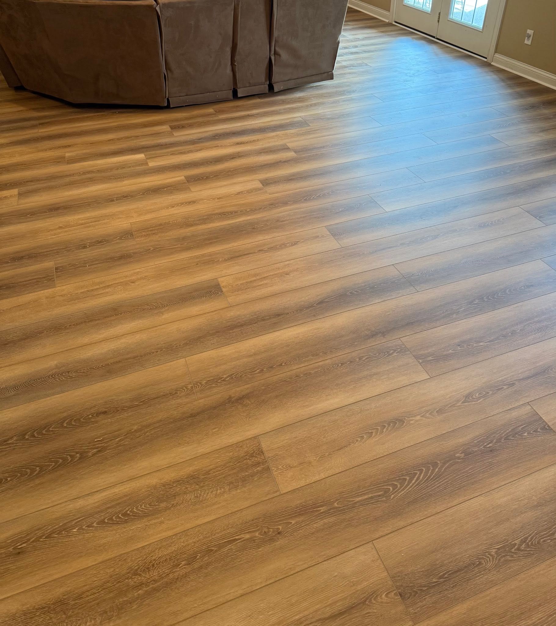 Honey wood-look flooring in a living room with a sectional sofa.