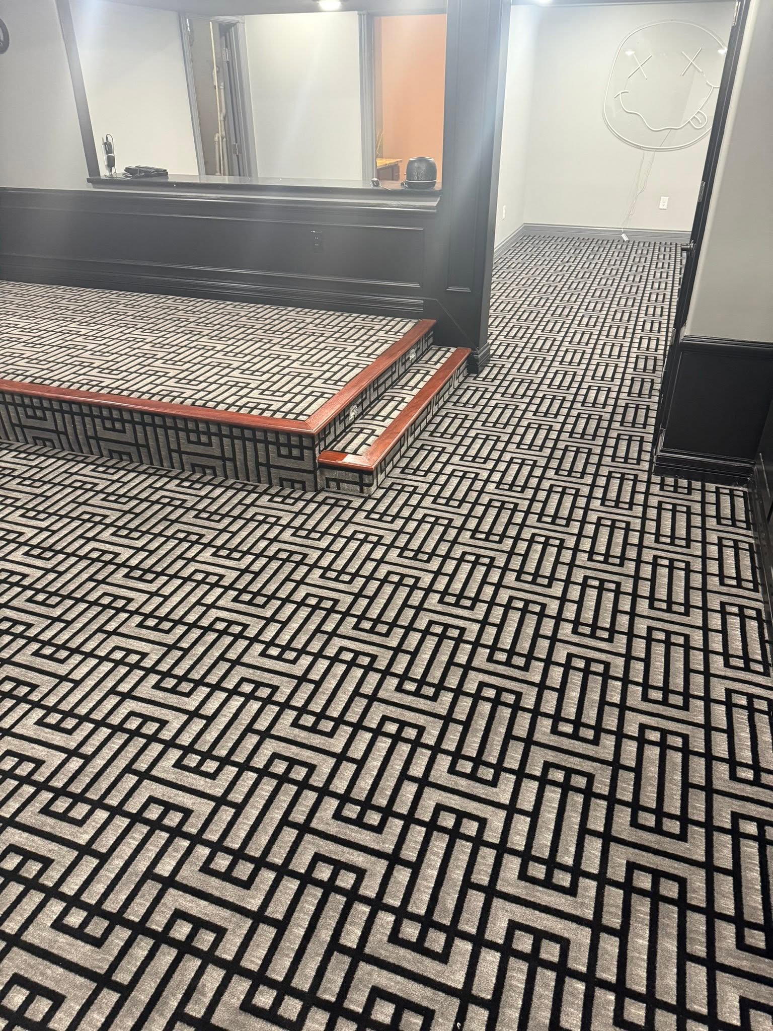 Charcoal and gray geometric-patterned carpet across a media room, stage, and steps.