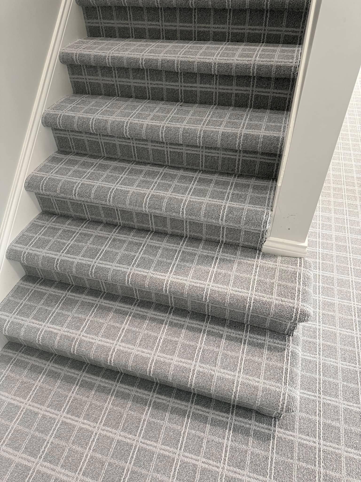 Gray plaid carpet on a staircase and landing.