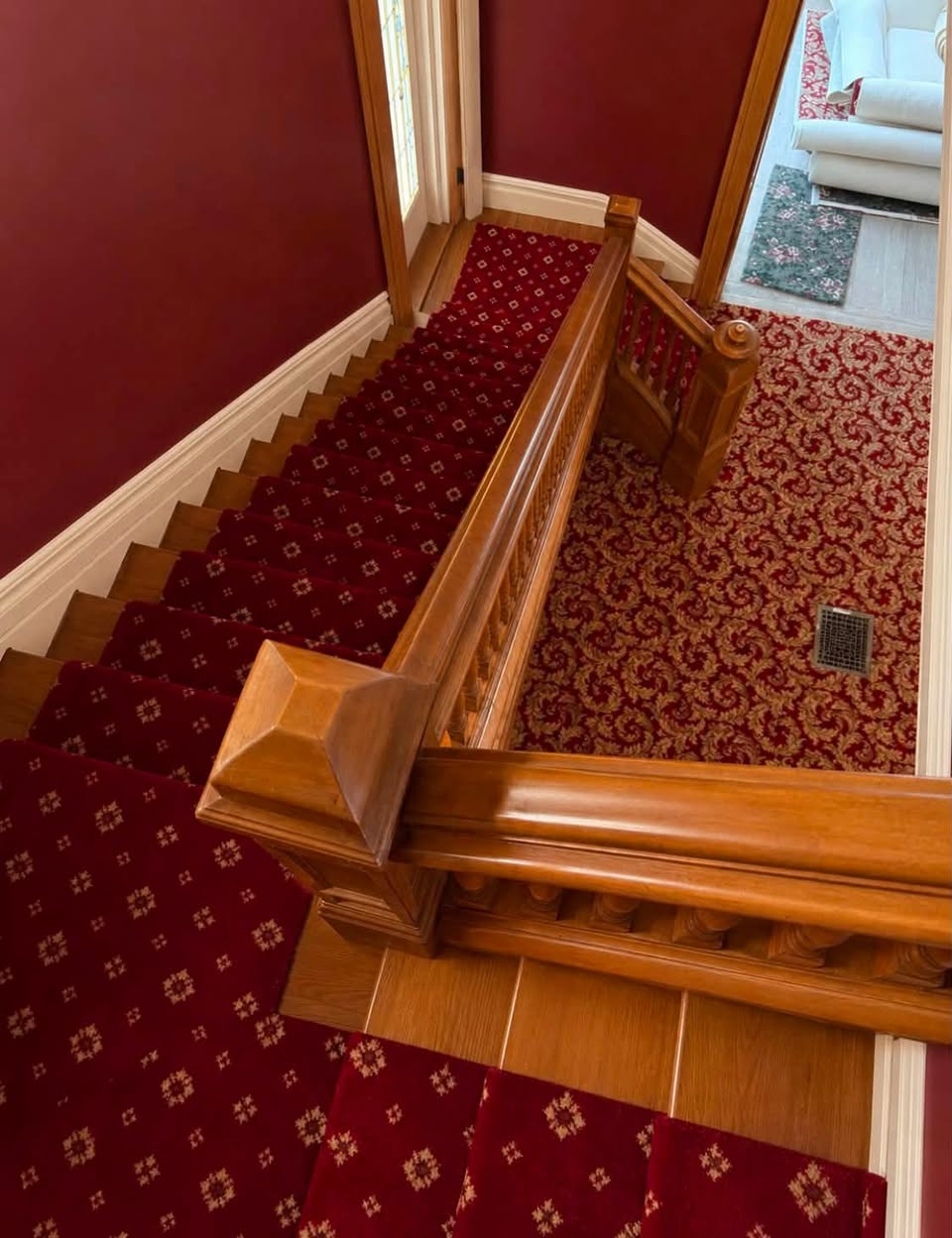Red patterned carpet on a staircase with a wood banister.