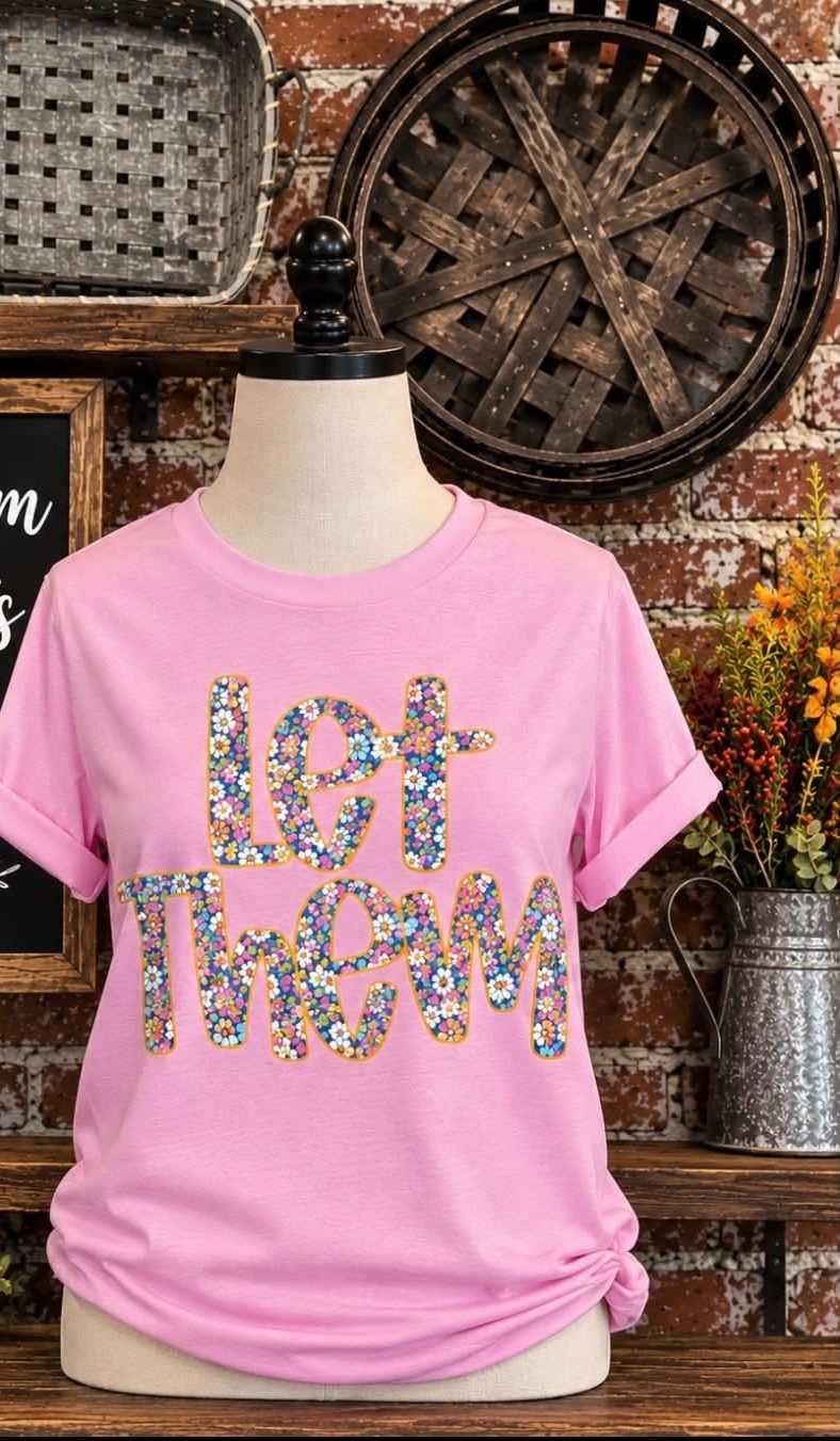 A pink floral Let Them graphic t-shirt on display.