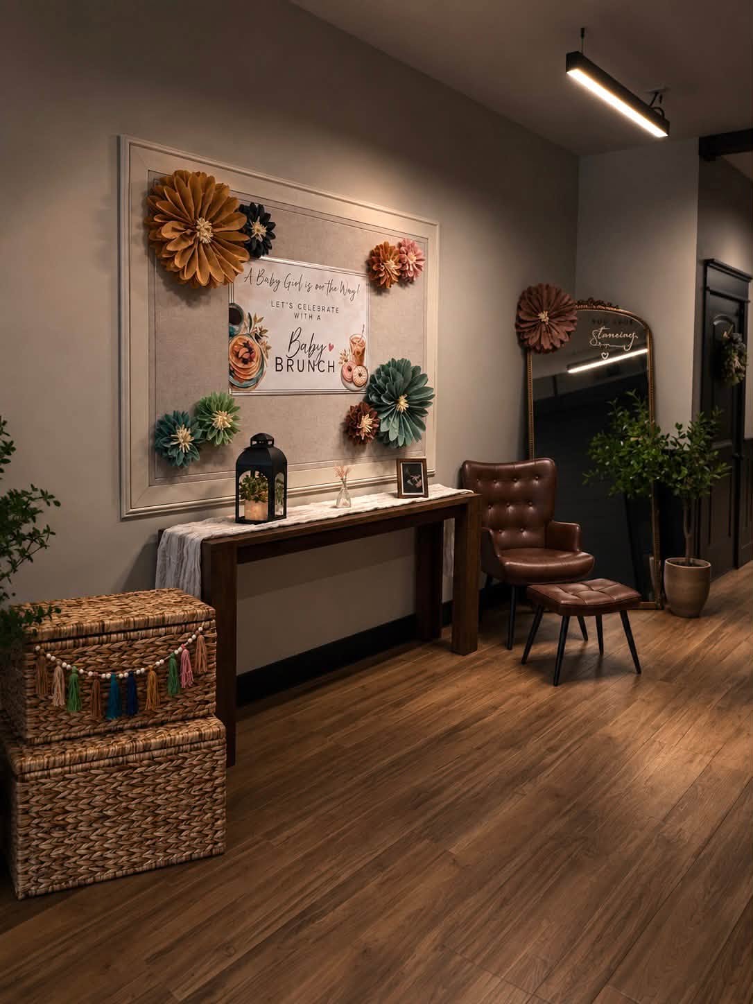 A baby brunch welcome display with paper flowers, a leather chair, and a gold mirror at The Venue.