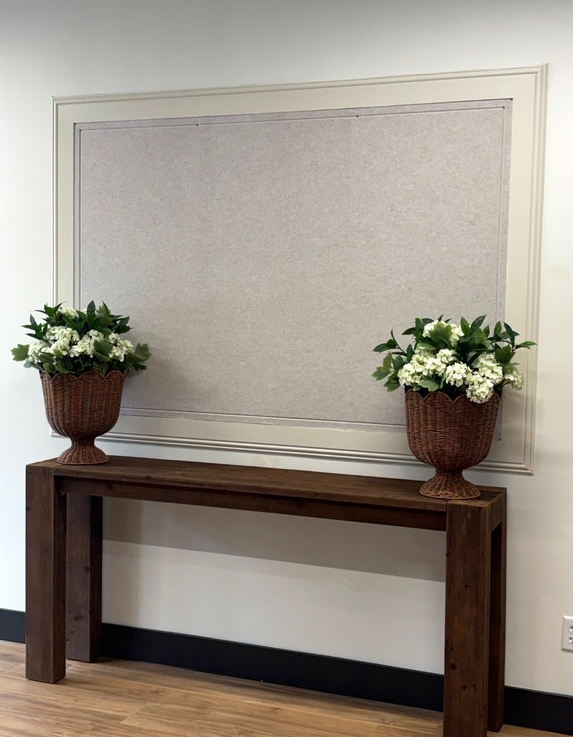 A styled console table with a display frame and fresh floral arrangements at The Venue.
